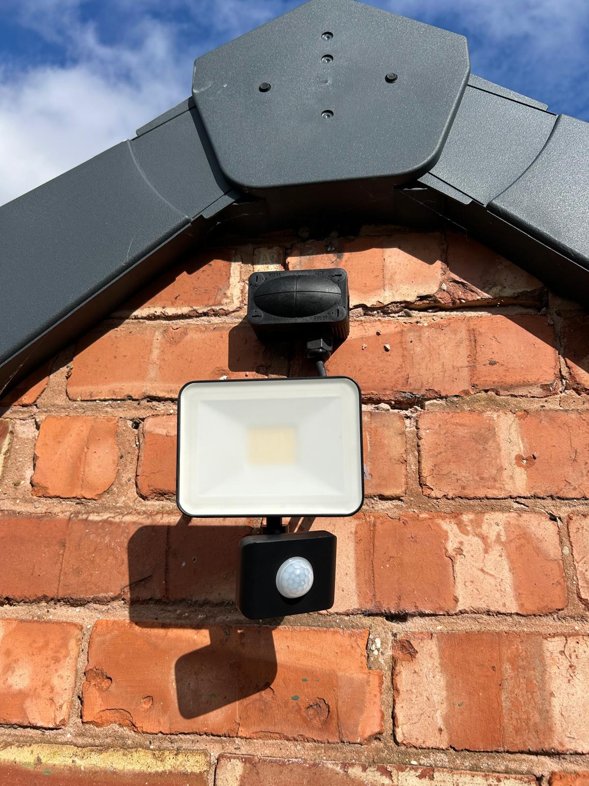 Modern PIR security floodlight fitted to a brick exterior